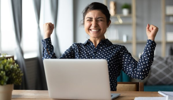 student happy sitting at laptop